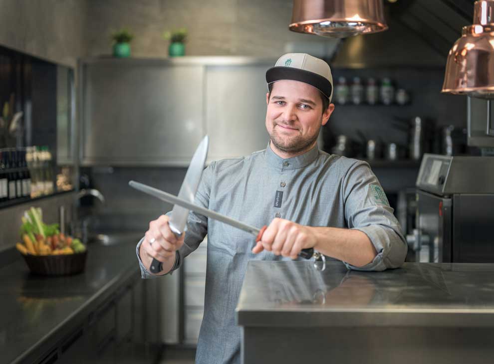 Chefkoch unGXUND mit Kapperl auf und (Wetz)Messer in der Hand